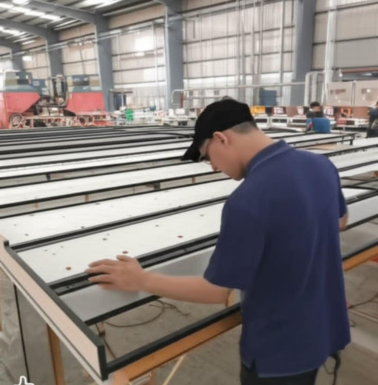 عامل يقوم بفحص ألواح MDF داخل ورشة KARMA Aluminium & MDF في مكناس.